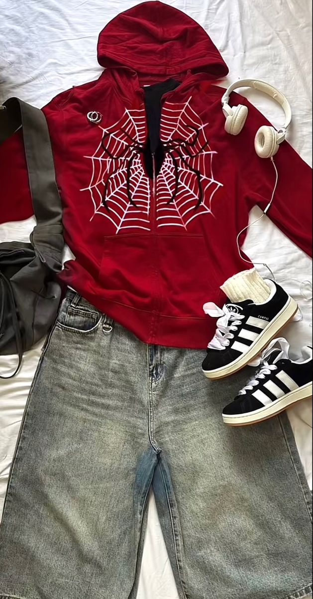 a red hoodie with spider webs on it and headphones laying next to shoes