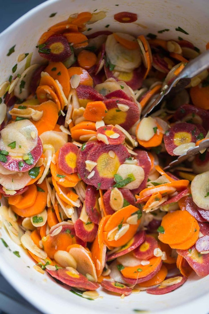 a white bowl filled with lots of different types of veggies next to a spoon