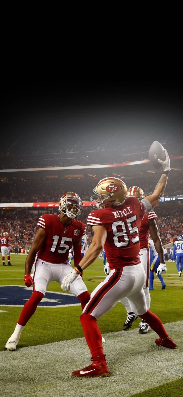 two football players in red and white uniforms are on the field with one holding a ball