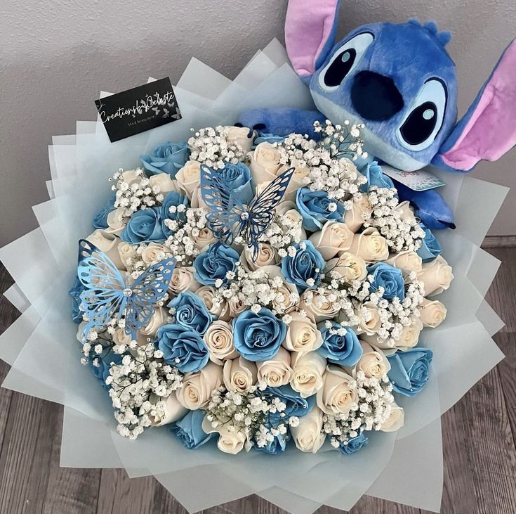 a bouquet of blue and white flowers with a stuffed animal