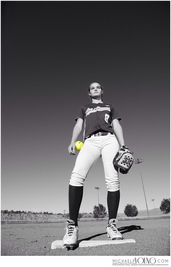 a female baseball player is holding a ball and glove