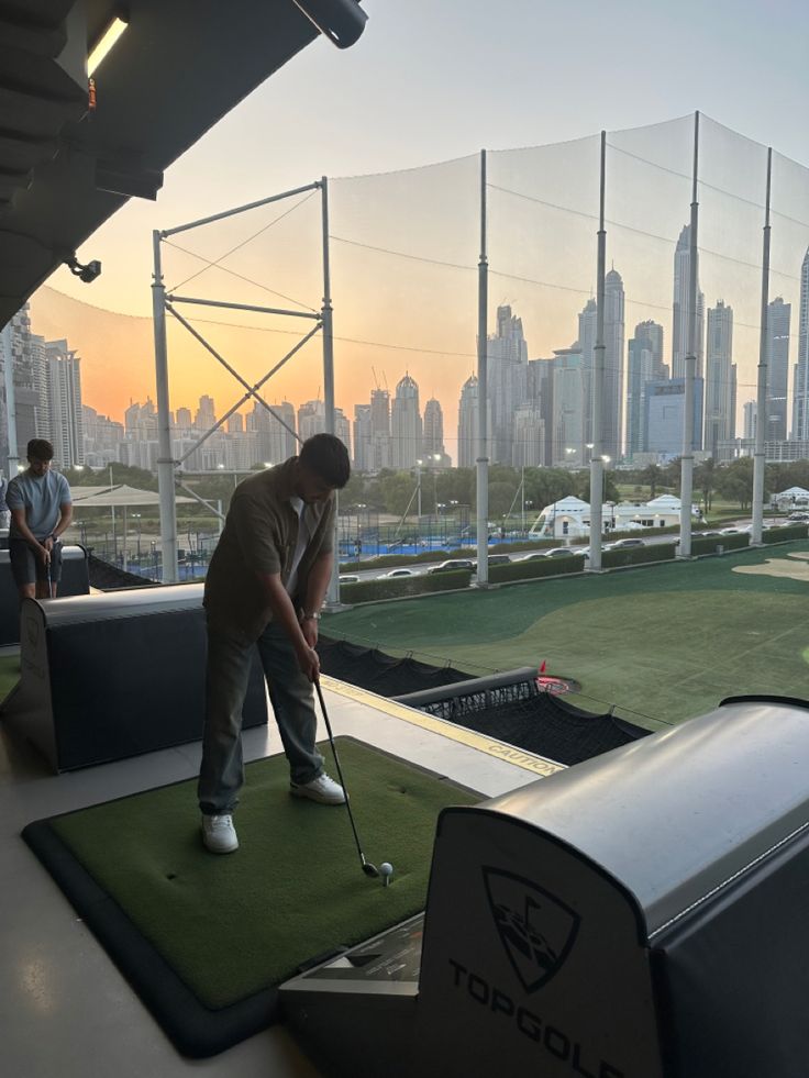 a man is playing golf at the top of a building in front of a cityscape