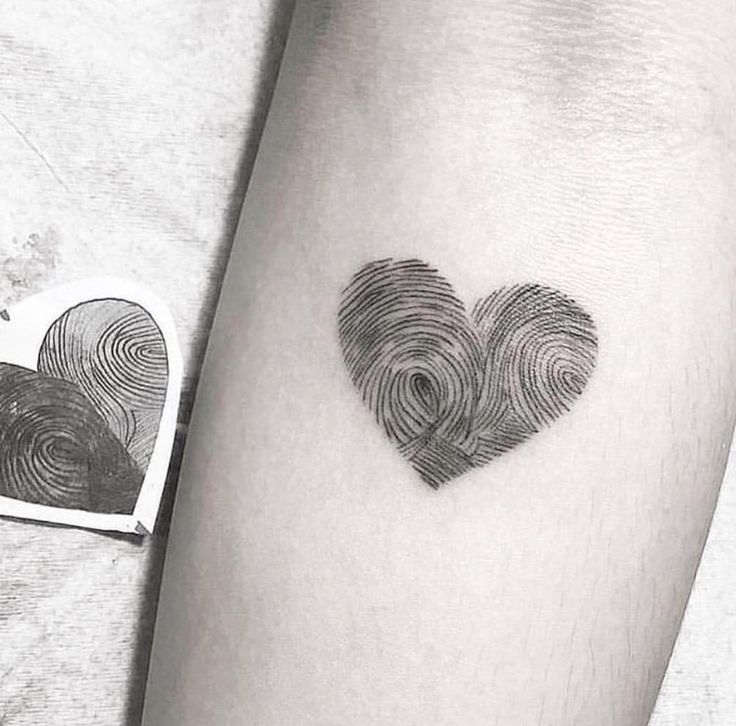 a heart shaped finger print tattoo on the left arm