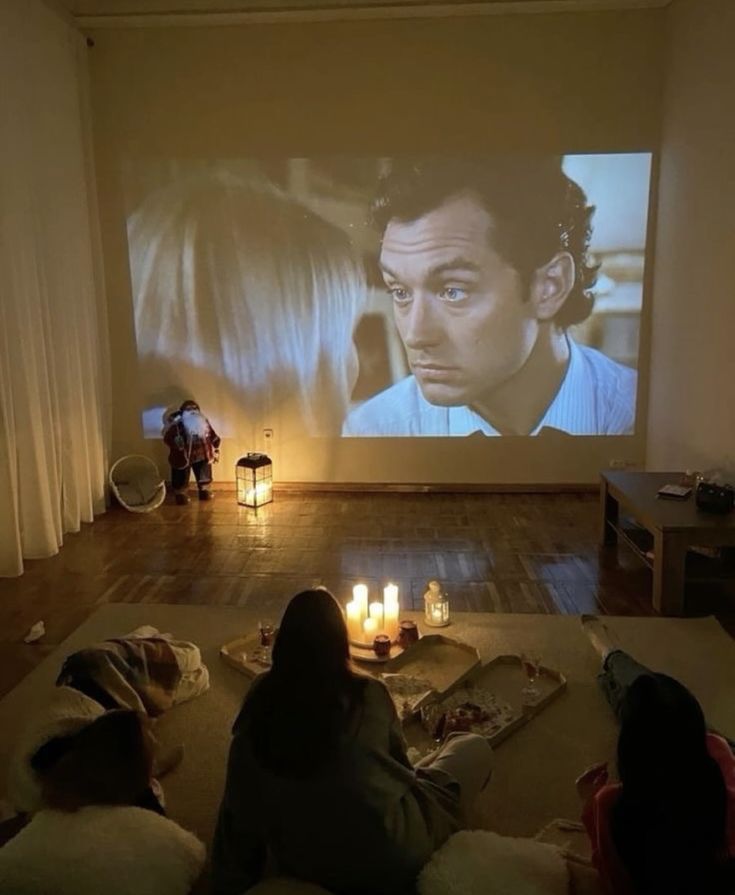 people sitting in front of a projector screen with candles on the floor next to them