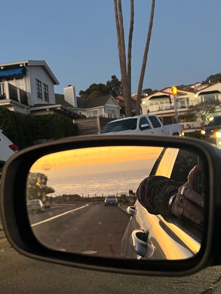 a rear view mirror on the side of a car with houses in the back ground