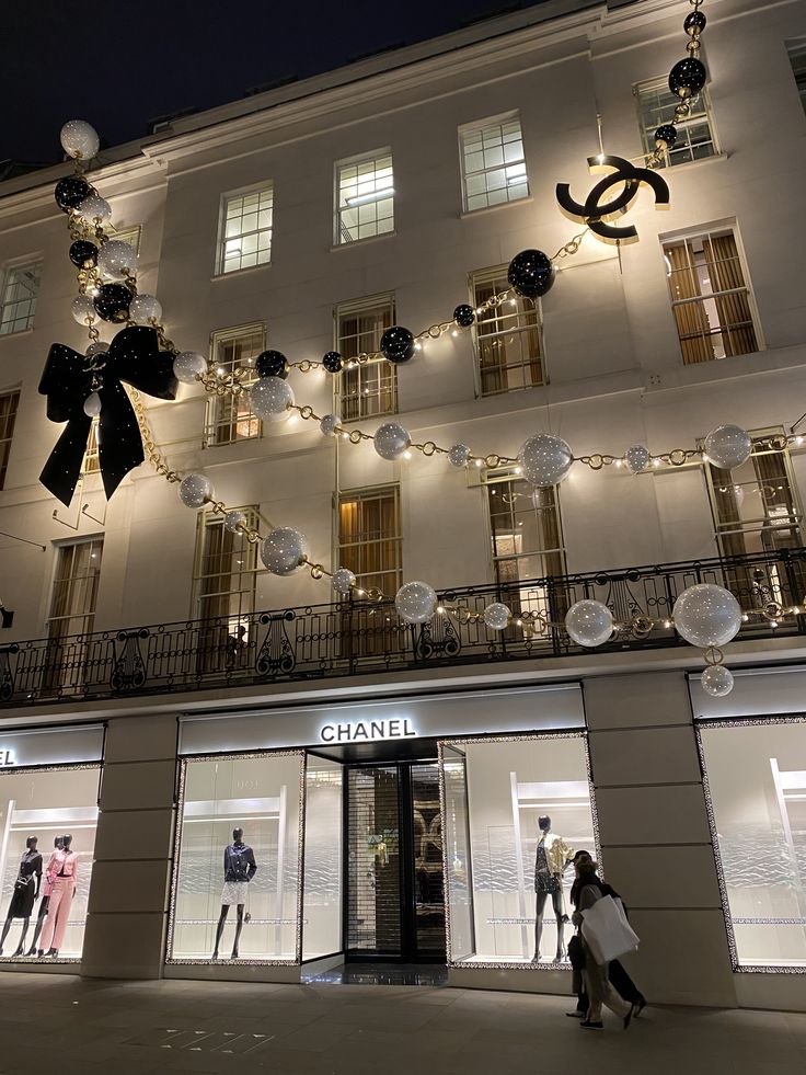 people walk past chanel boutiques decorated with christmas lights