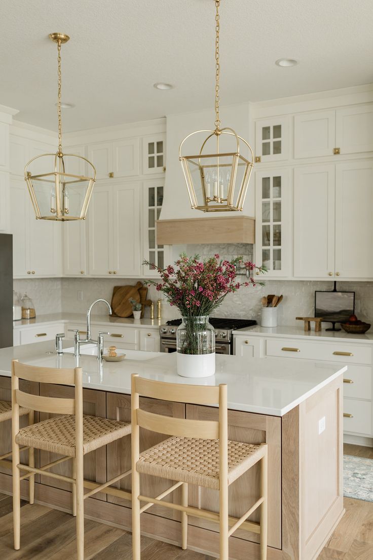 a large kitchen with white cabinets and wooden chairs in the center island, two pendant lights hanging from the ceiling