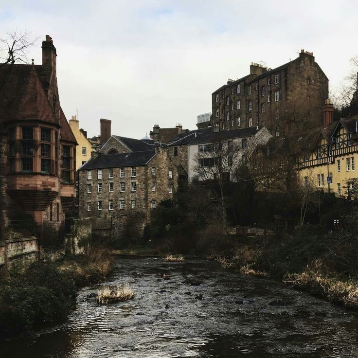 a river running through a small town next to tall buildings and bricked homes on either side