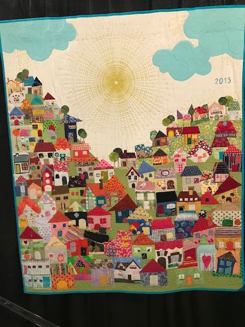 a quilted wall hanging with houses on it