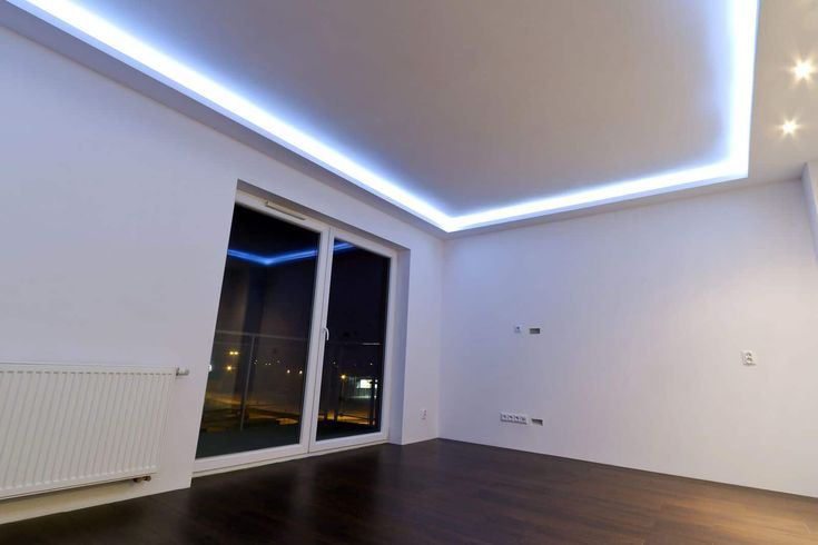 an empty room with wood flooring and white walls, lights on the ceiling and sliding glass doors