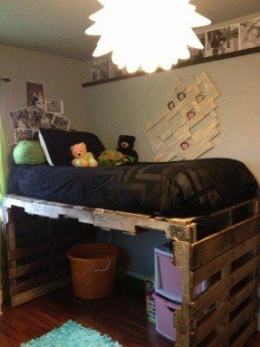 a loft bed made out of wooden pallets in a room with green curtains and pictures on the wall