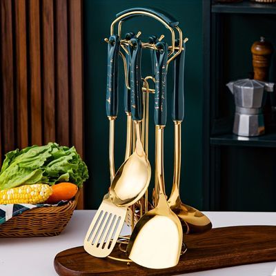 gold utensils and spoons are on a wooden tray next to a basket with vegetables