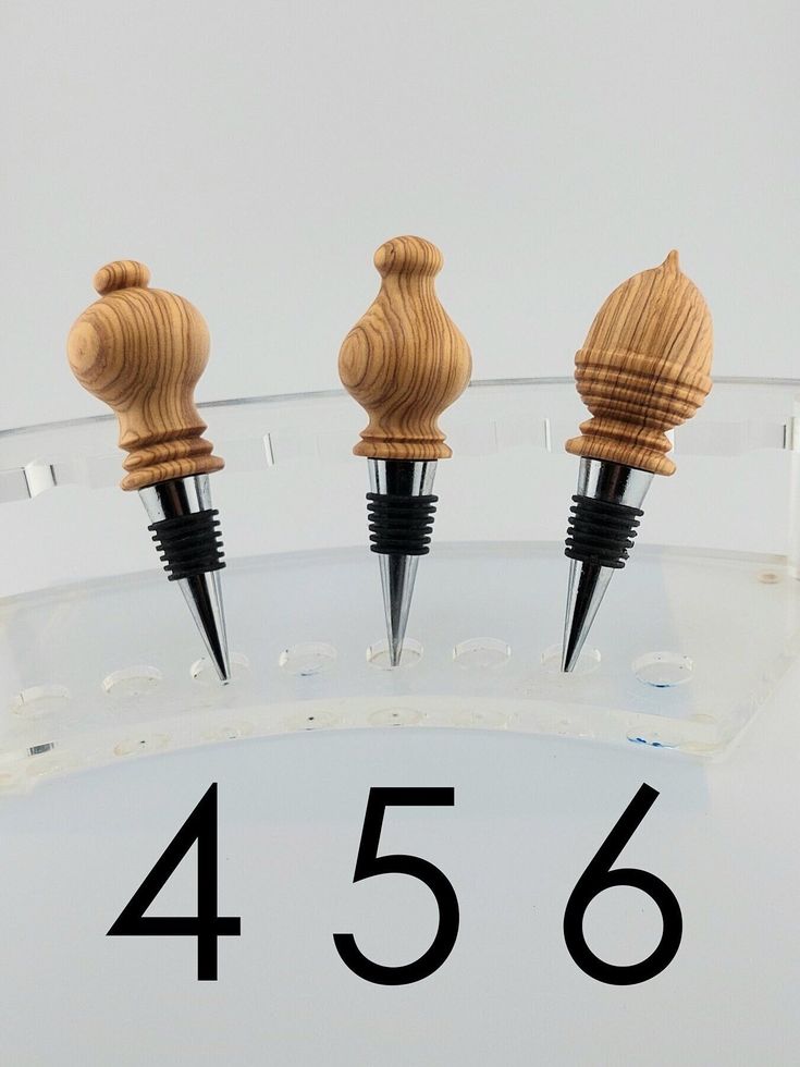 three wooden stoppers sitting on top of a clear glass shelf with numbers below them