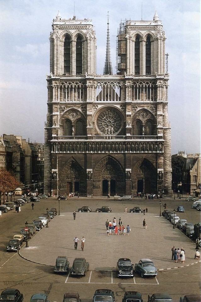 cars are parked in the parking lot near an old building with two large cathedrals