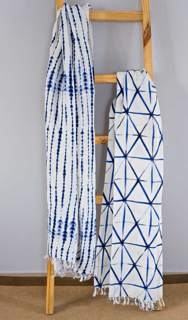 two blue and white scarves hanging on a ladder