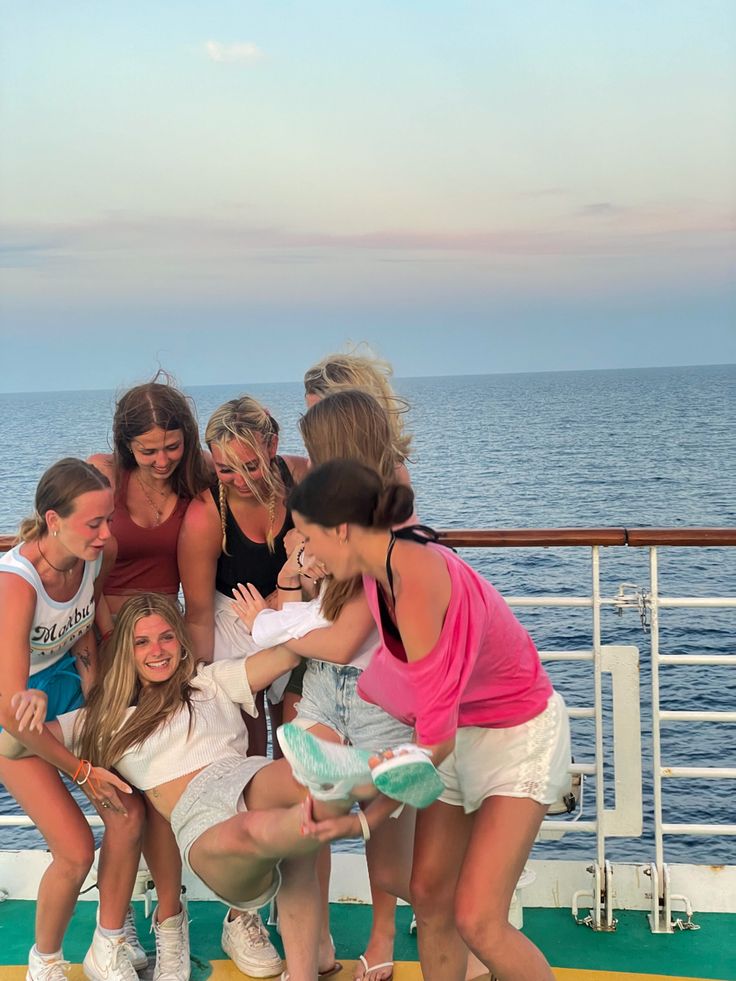 a group of young women standing next to each other on a boat in the ocean