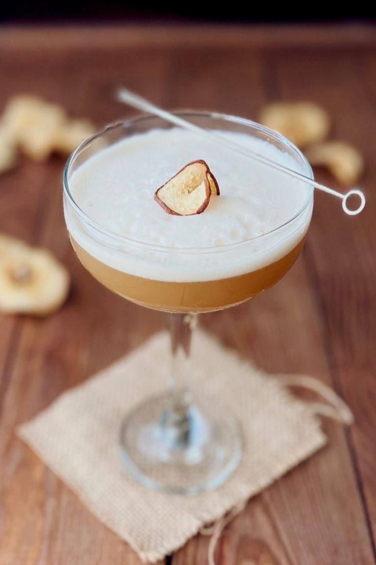 a drink in a glass on top of a wooden table next to some crackers