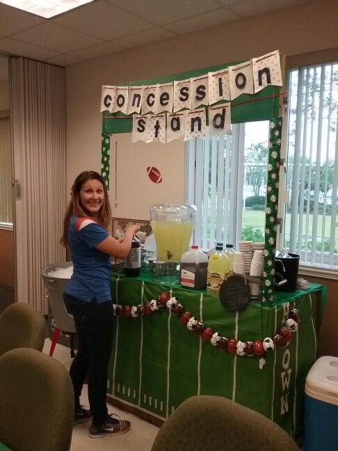 a woman standing in front of a green table with food on it and decorations hanging from the ceiling