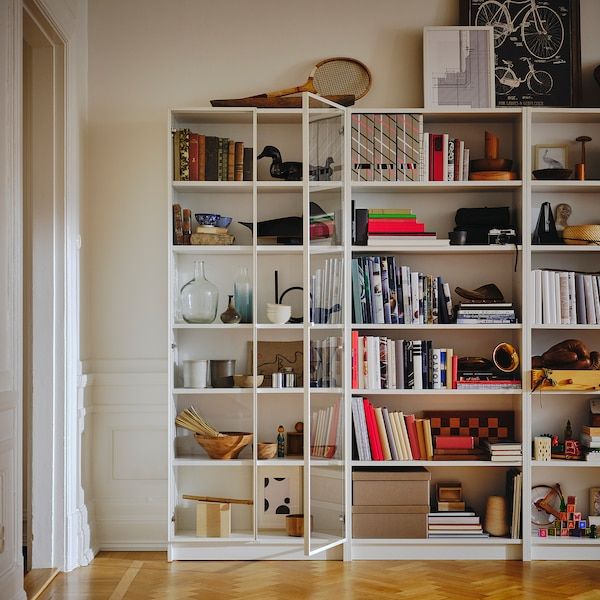 a white bookcase filled with lots of books on top of a hard wood floor