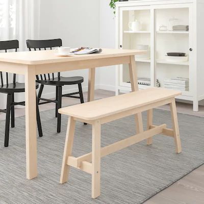 a wooden table with two black chairs and a white bookcase in the back ground