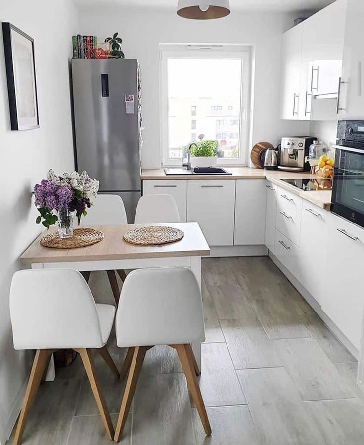 a kitchen with white cabinets and wooden table in front of a refrigerator, stove top oven and dishwasher