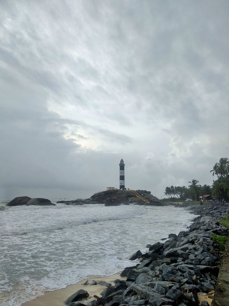 a light house sitting on top of a rocky beach next to the ocean with waves coming in