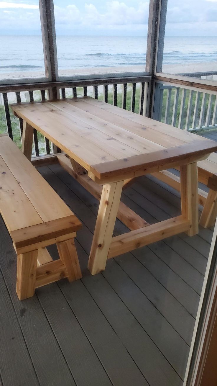 a wooden picnic table sitting on top of a porch