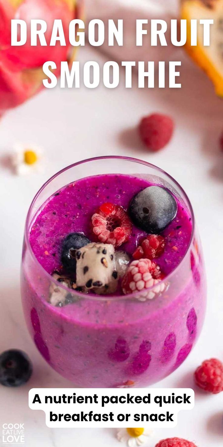 a smoothie in a glass with berries and blueberries on top, next to some fruit