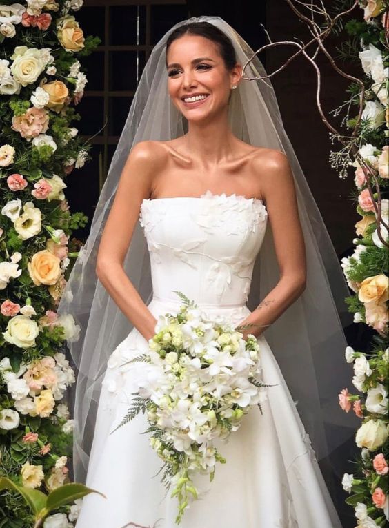 a woman in a wedding dress standing under a floral arch