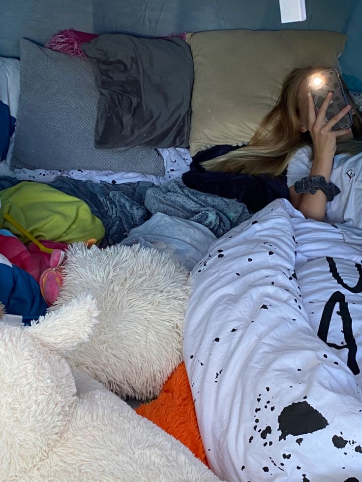 a woman laying in bed with lots of pillows and blankets on top of her head