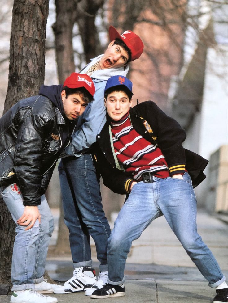 three young men posing for a photo in front of a tree with one man on his head