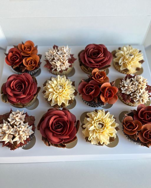 cupcakes decorated with red and yellow flowers in a box