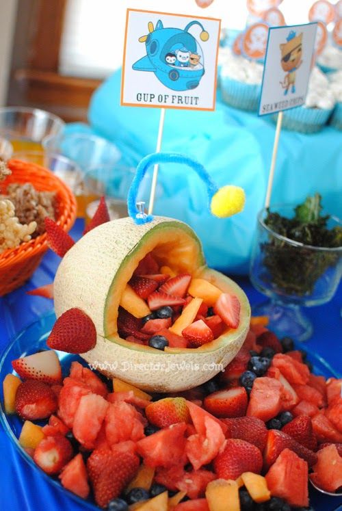 a blue table topped with fruit and cupcakes