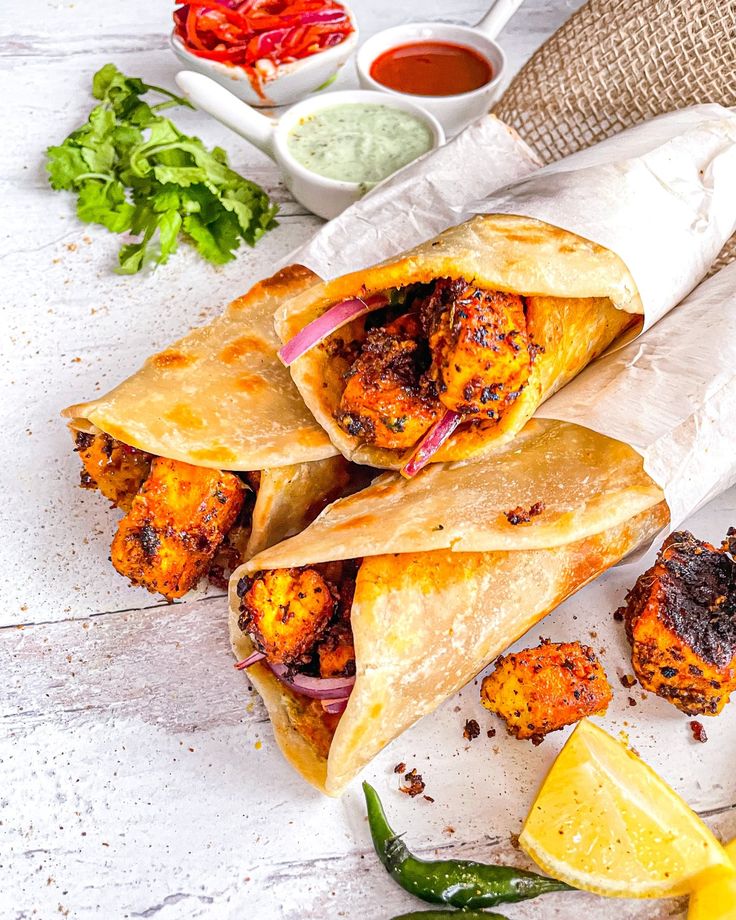 three pita breads on a plate with some dipping sauce and lemon wedges