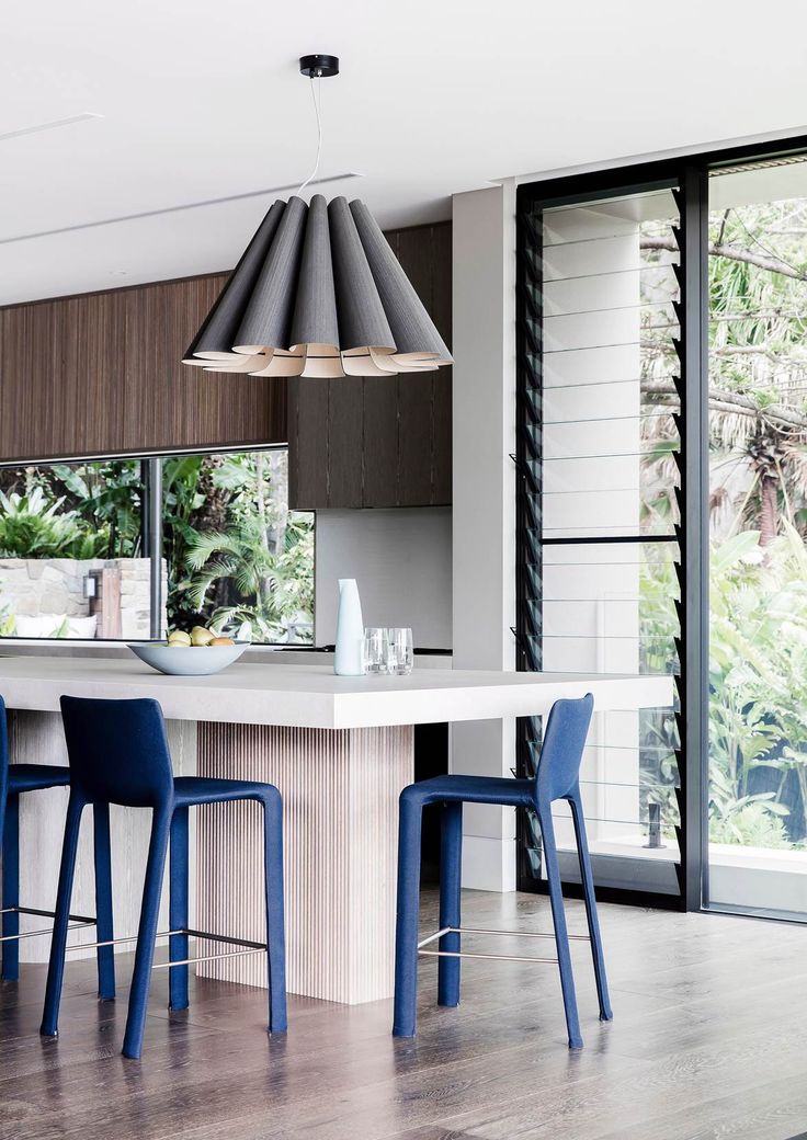 an image of a modern kitchen setting with blue chairs and bar stools in the center