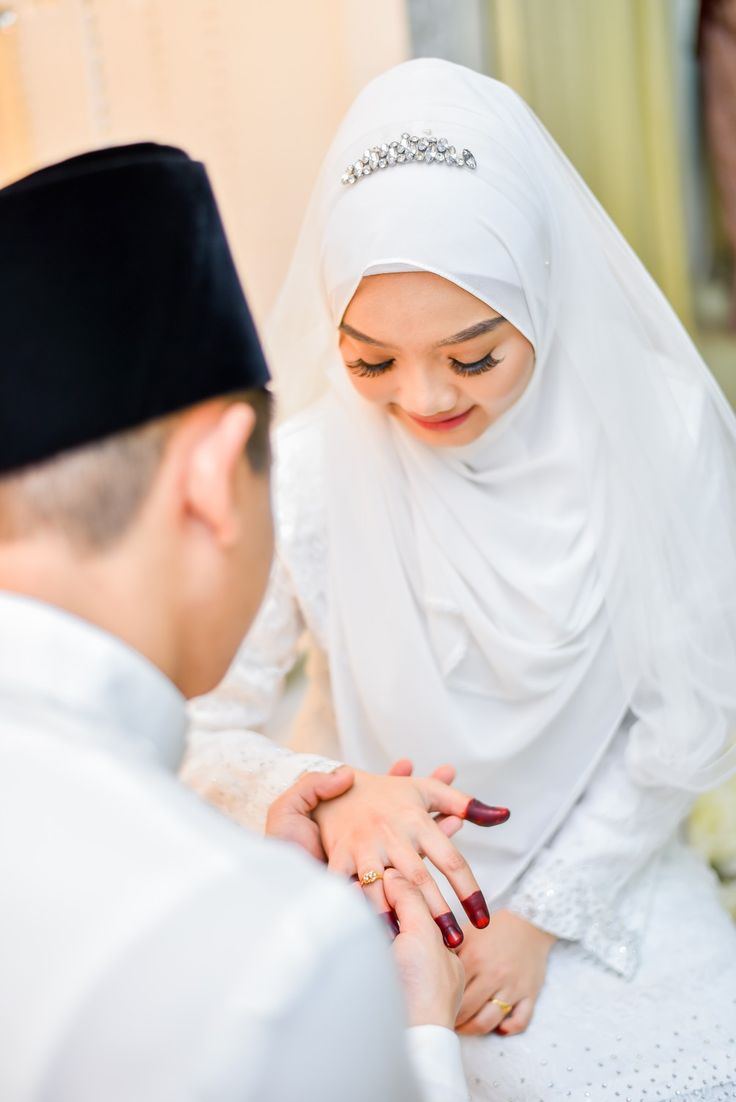 a young man and woman dressed in traditional muslim garb, holding hands with each other