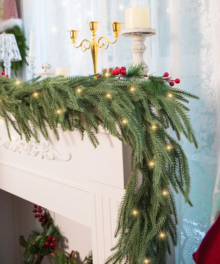 a mantel decorated with christmas greenery and candles