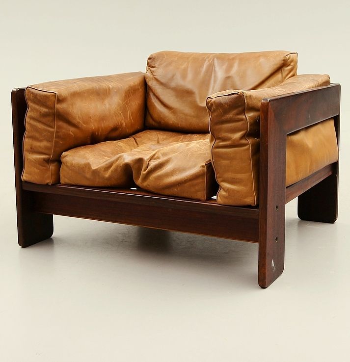 a brown leather chair sitting on top of a white floor next to a wooden frame