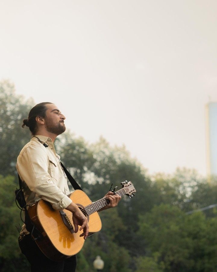 a man with dreadlocks playing an acoustic guitar