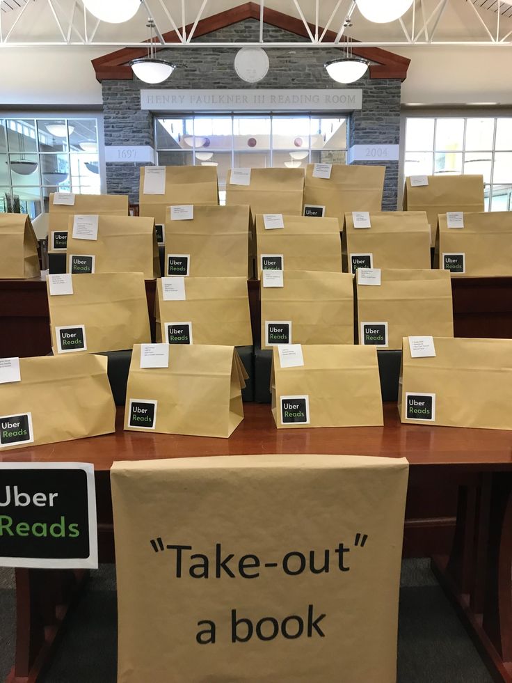 there are many brown paper bags on the table and one has a sign that says take - out a book