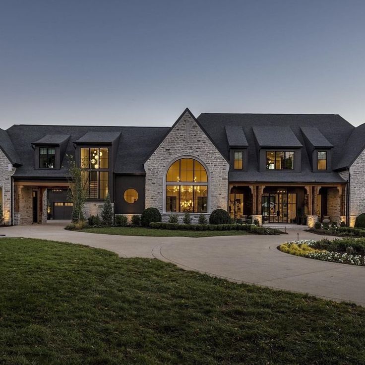 a large house lit up at night with lights on the windows and grass in front