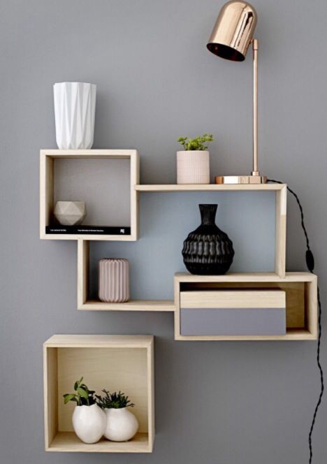 some shelves with vases and other items on them against a gray wall in a living room