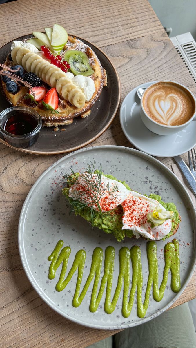 two plates with food on them sitting on a table next to a cup of coffee