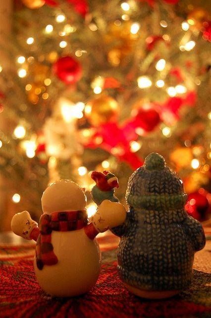 two snowmen sitting next to each other in front of a christmas tree