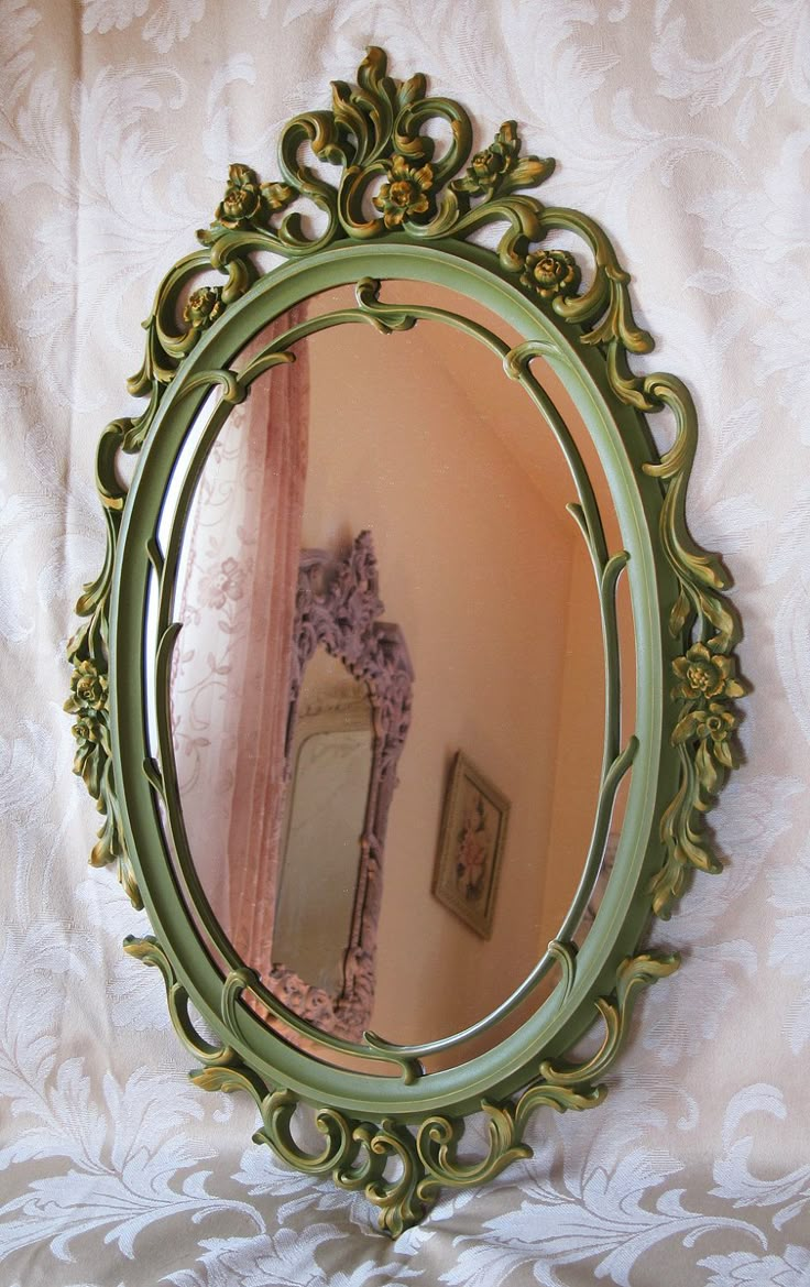 a green mirror sitting on top of a bed next to a white curtain and wall