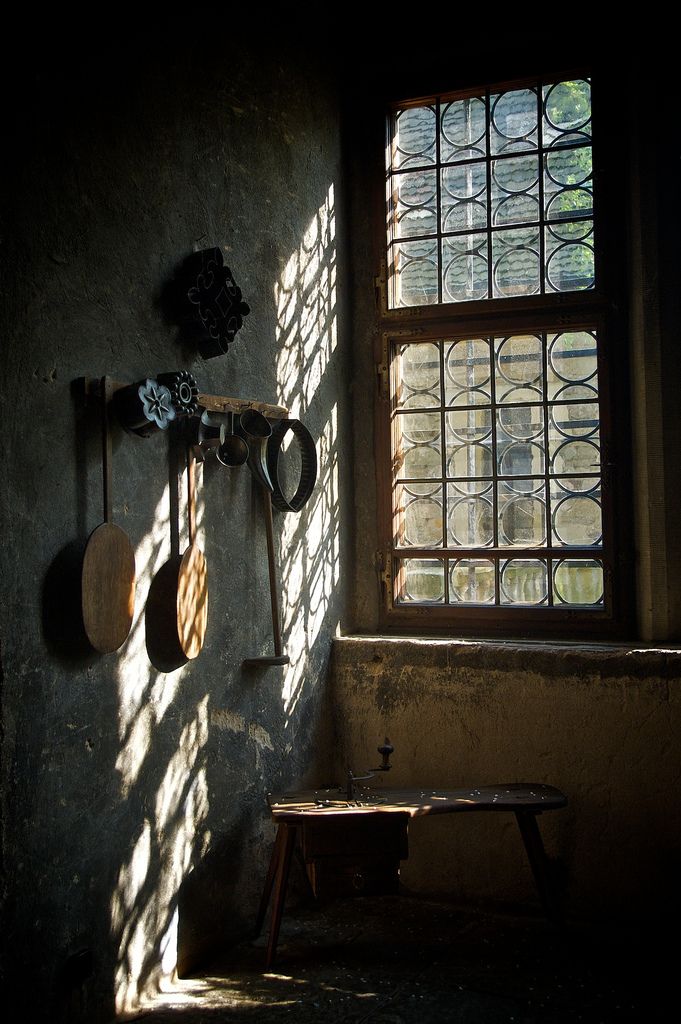 the sun shines through two windows in an old building with tools hanging on the wall