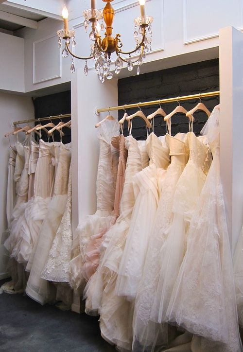 there are many dresses hanging on the rack in front of the chandelier,