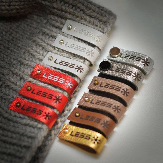 several different colored tags are attached to a gray knit sweater with gold, silver and red accents