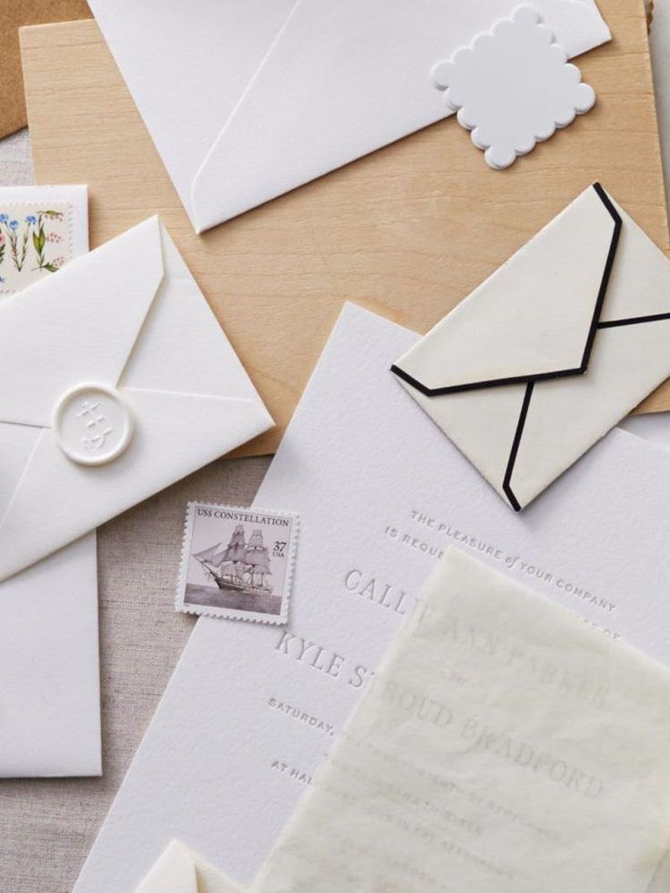 many different types of envelopes and stamps on a table with one letter in the middle