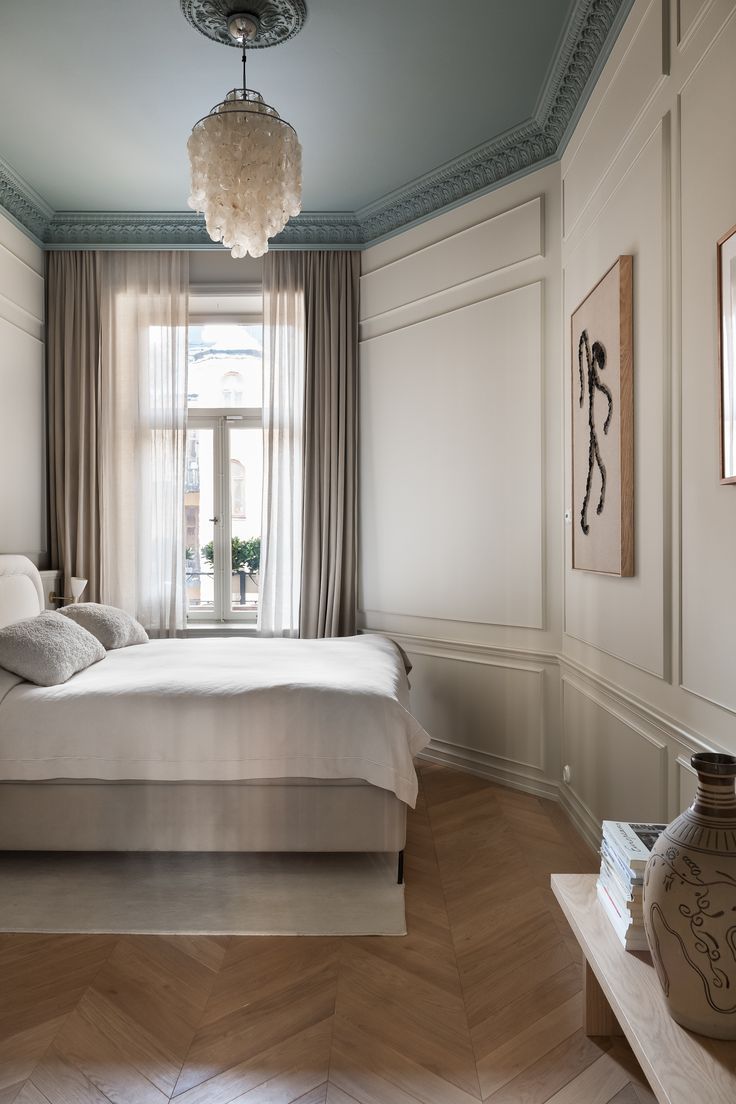 a bedroom with a large bed in the corner and a chandelier hanging from the ceiling